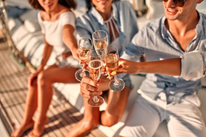 3 young people making health with a glass of champagne on a boat